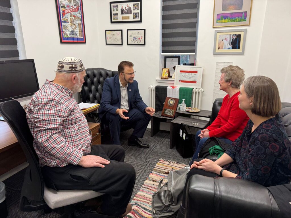 Afzal sat speaking with three people in an office