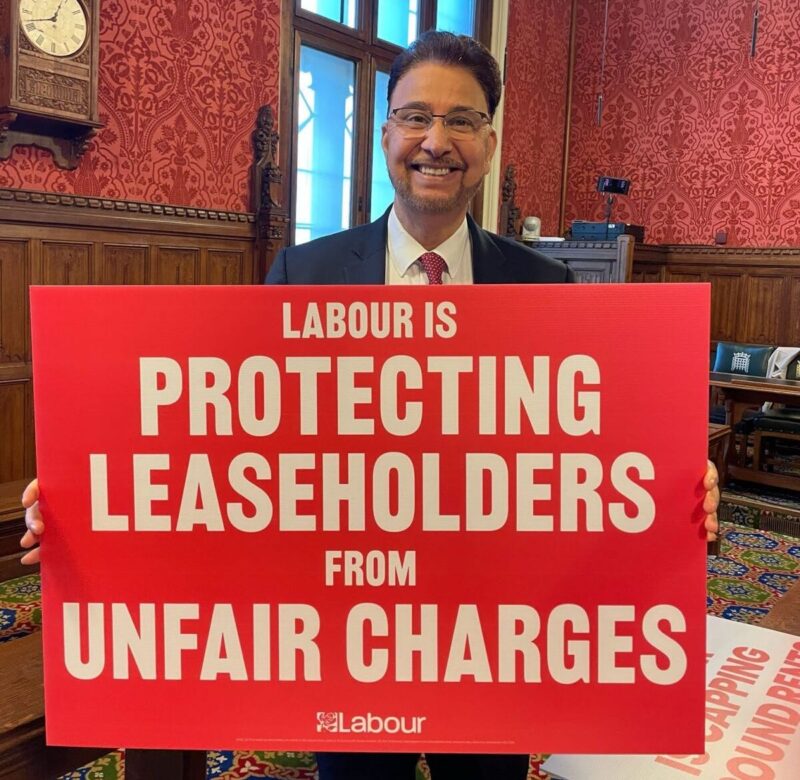 Afzal Khan MP holding a sign which reads "Labour is protecting leaseholders from unfair charges"